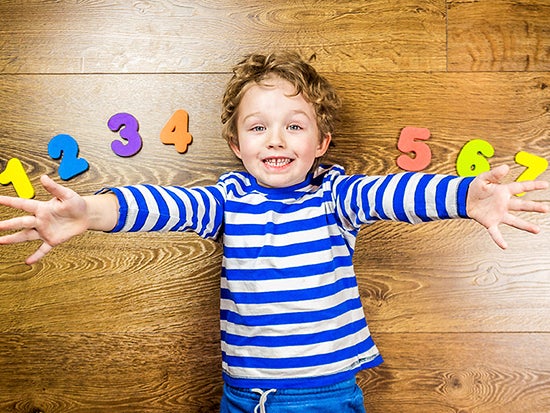 Kid lying on floor with arms spread out with numbers one through seven spread around him