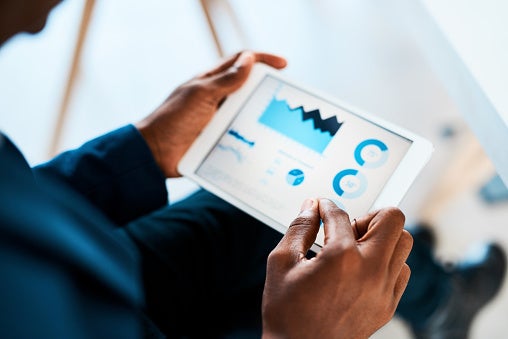 Person looking at a tablet with graphs on it.