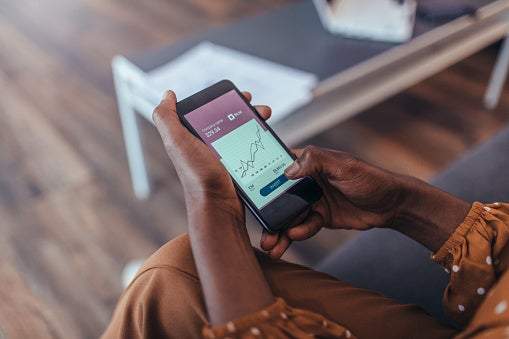 Person sitting down looking at their phone that is displaying a graph