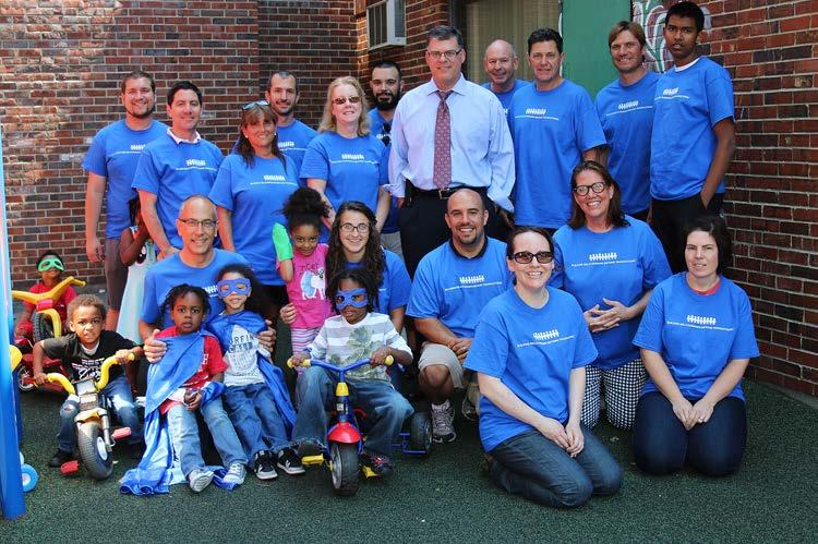 President and CEO of Cambridge Savings Bank Wayne Patenaude posing for a photo with local volunteers at Children of Our Place daycare