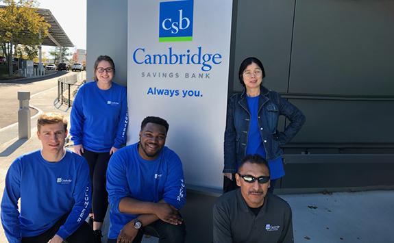 5 CSB volunteers posing beside a CSB sign