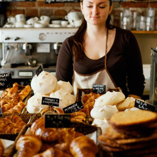 Young female employee standing behind the counter of a bakery