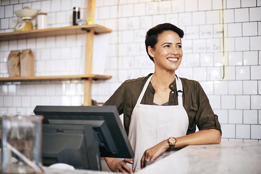 Woman business owner standing behind counter.