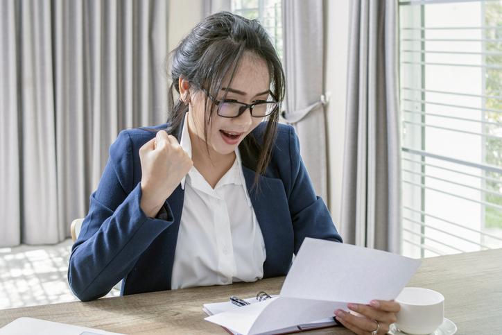 A woman smiling and holding a letter