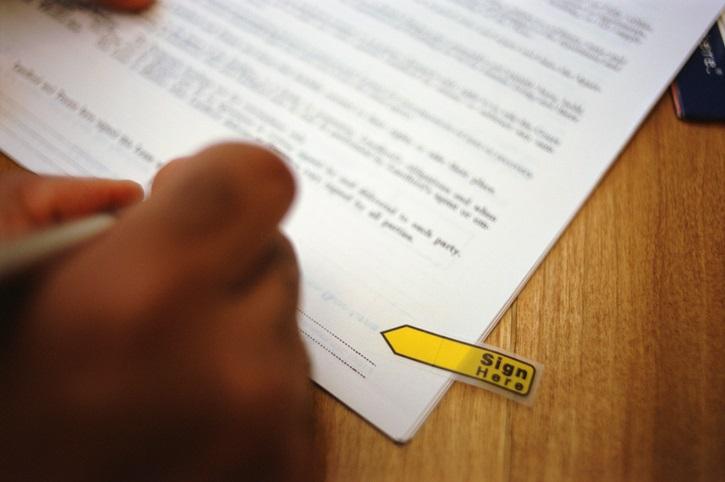 A person's hand signing a contract