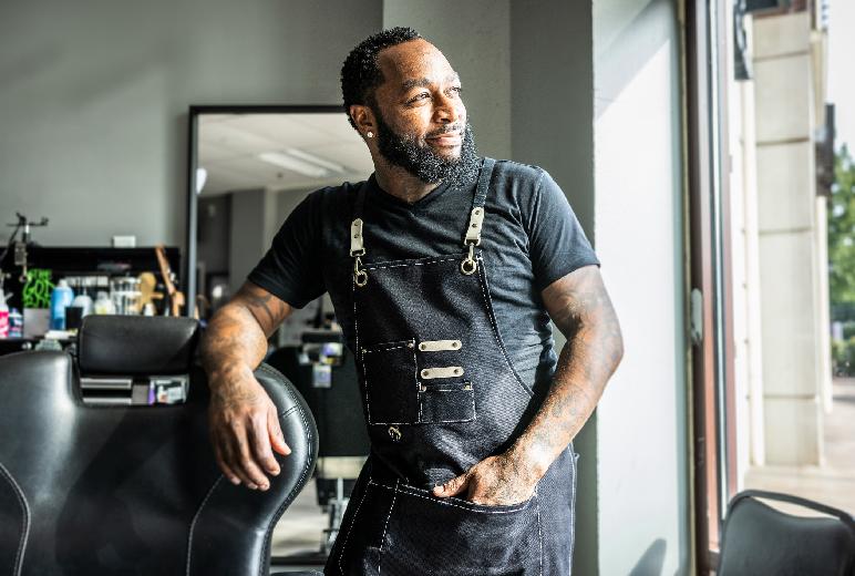 A barber looking out the window of his shop. Click to view directories of local Black-owned businesses